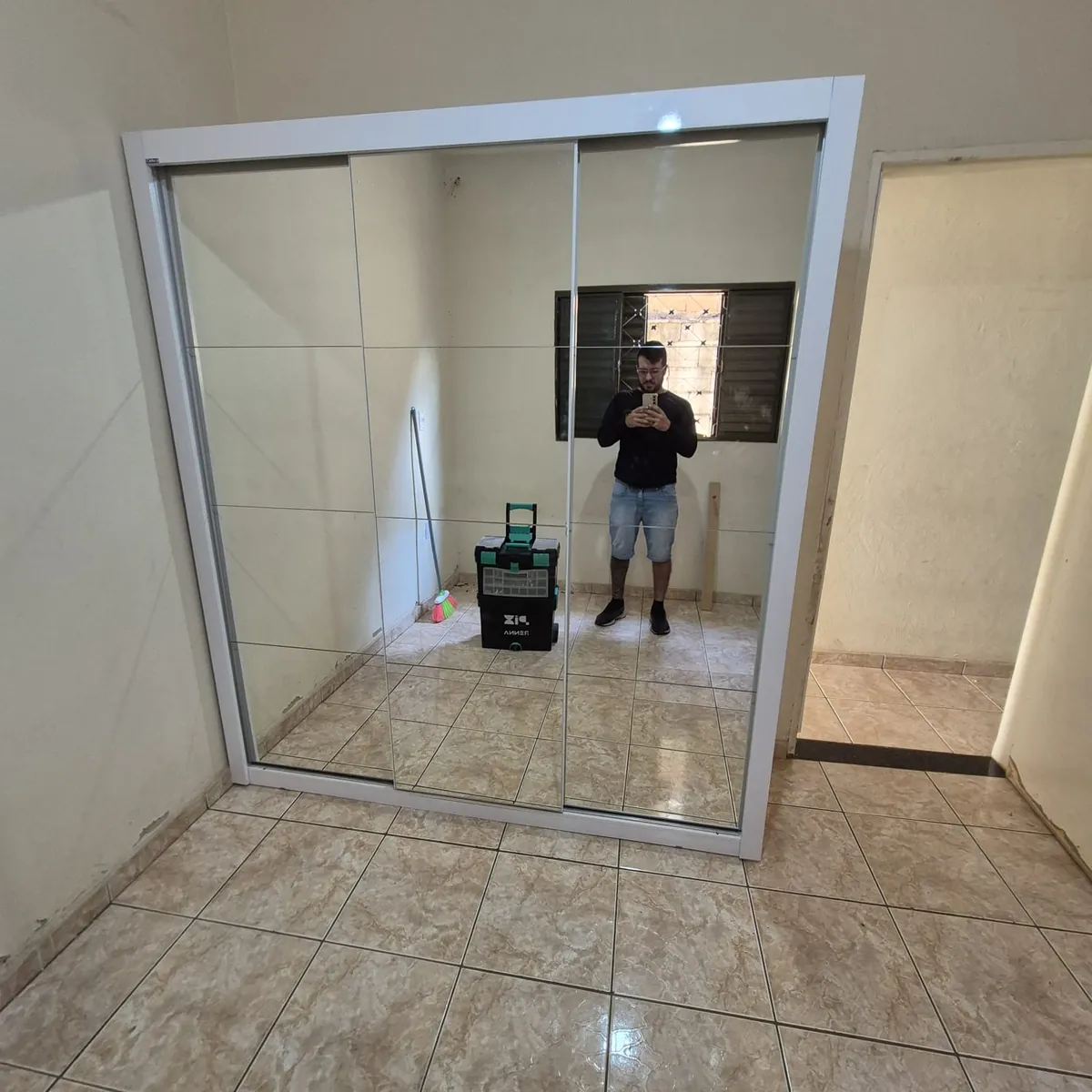 Marcelo Ribeiro ao lado de um guarda-roupa com portas de espelho recém-montado